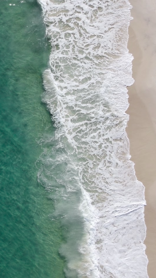 Aerial view of ocean surf meeting the shore
